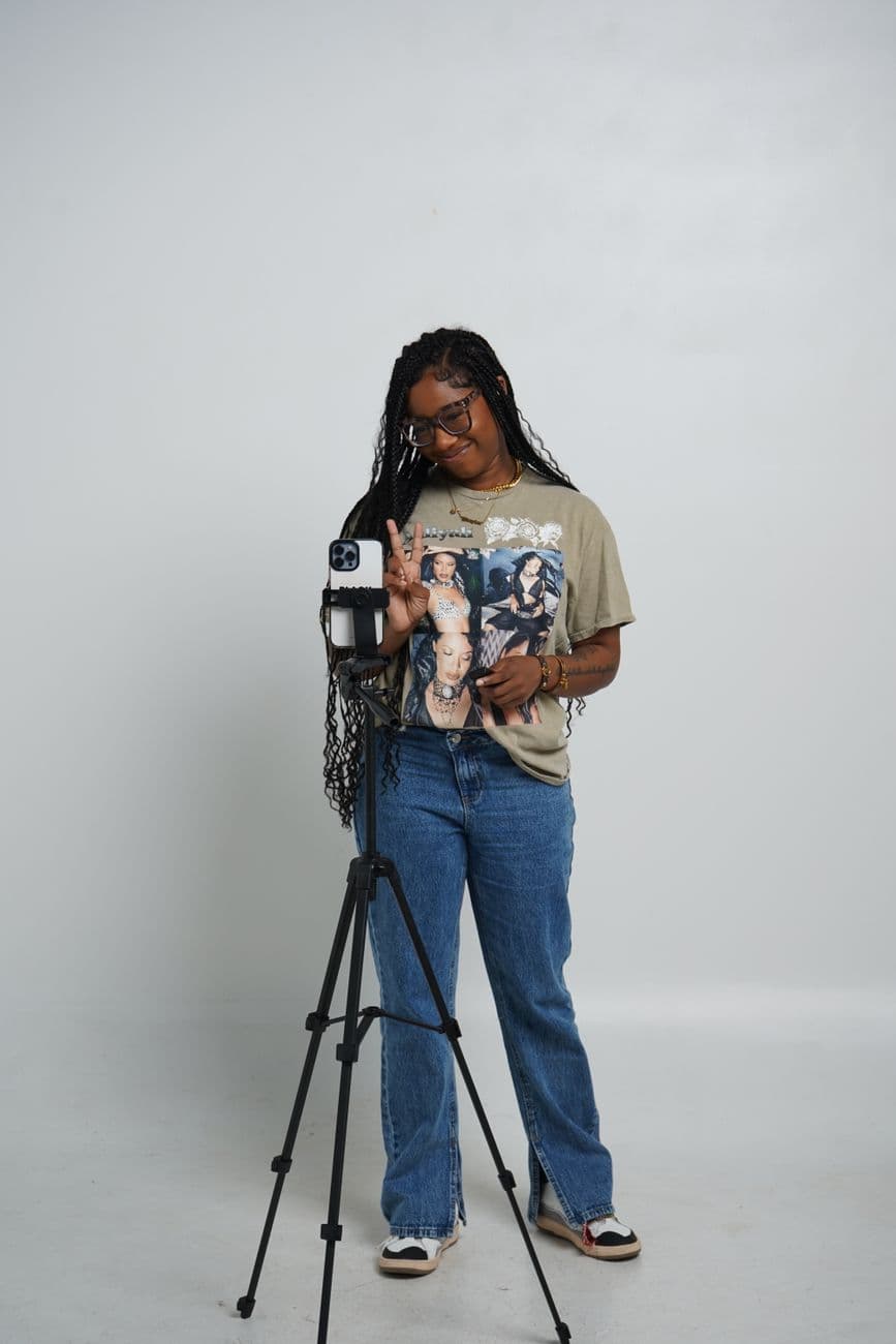 Young woman posing with a camera on a tripod in a well-lit studio. · Brianna Taylor #33568641